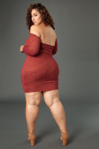 Full figured woman with curly hair in tight dress looking over bare shoulder