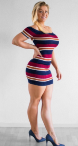 Curvy blonde model in tight short striped dress and high heels. Standing with hand on hip smiling